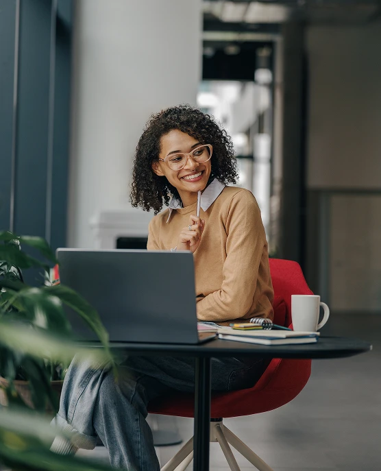 Smiling female entrepreneur working on laptop while sitting in office near window